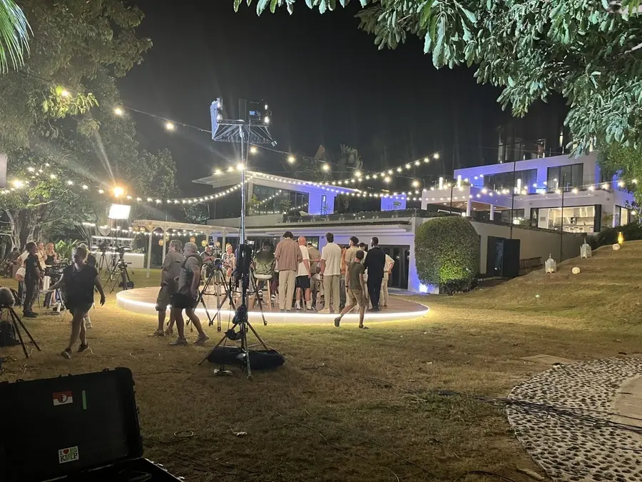 A night shoot with rigged lighting across an outdoor venue.